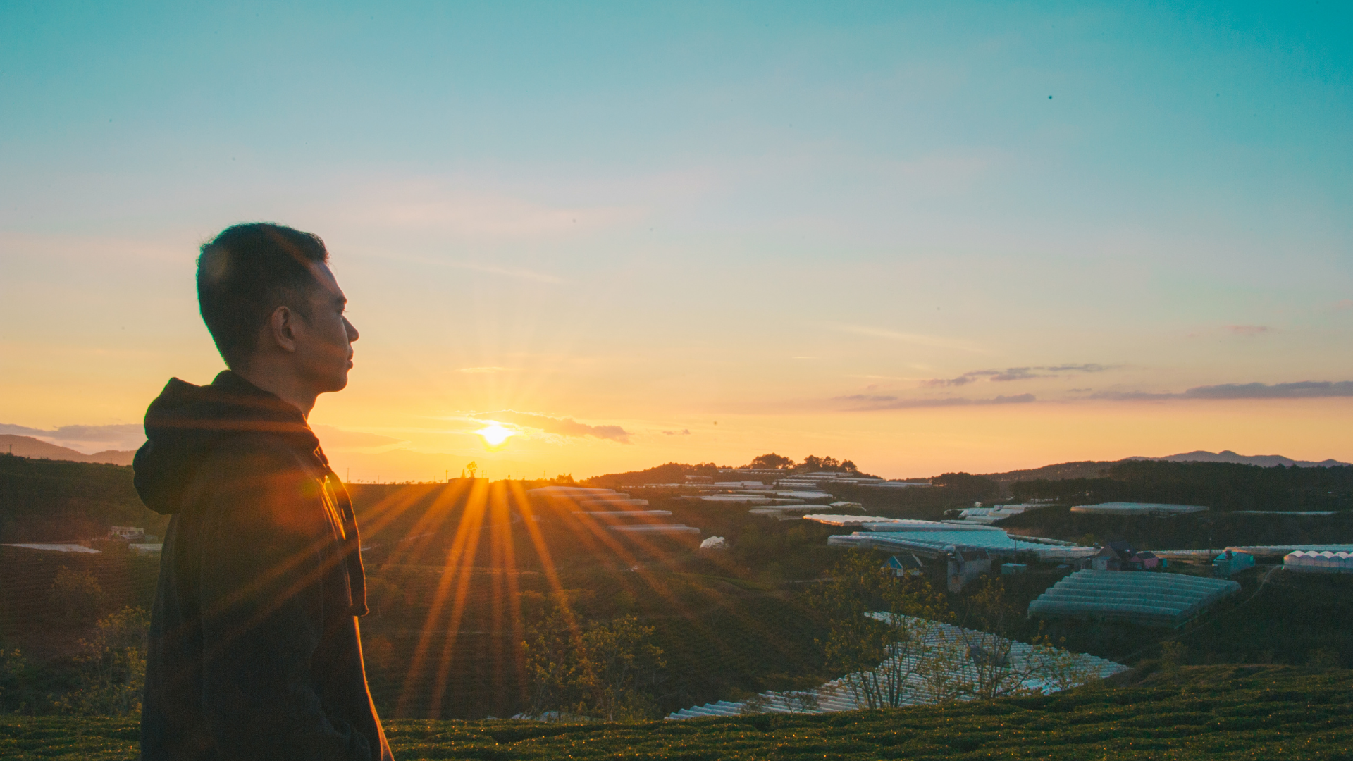 baner zdjecie zachod slonca nad horyzontem na pierwszym planie cjhlopoec stojacy bokiem i patrzacy w dal